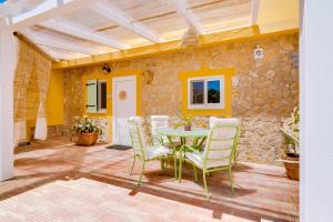 a patio with a table and chairs and a stone wall at Quinta Almargem Lusitano - Farm House in Tavira