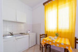 a small kitchen with a table and a yellow curtain at Apartments Dia in Dubrovnik