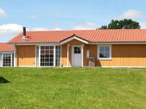 een huis met een oranje dak en een groene tuin bij 6 person holiday home on a holiday park in Gr sten in Gråsten