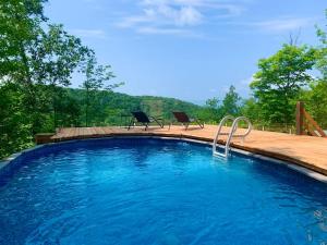 - une piscine avec deux chaises assises sur une terrasse en bois dans l'établissement Blue Hill Pool spa game room mountain view, à Morin Heights