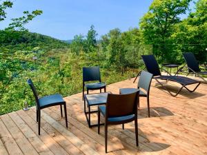 un groupe de chaises et de tables sur une terrasse dans l'établissement Blue Hill Pool spa game room mountain view, à Morin Heights