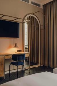 a hotel room with a bed and a desk and a tv at Flaner Hotel, WorldHotels Crafted in Warsaw