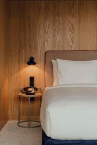 a bedroom with a bed and a table with a phone at Flaner Hotel, WorldHotels Crafted in Warsaw