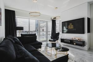 a living room with a black couch and a tv at Platinum Towers J&K in Warsaw