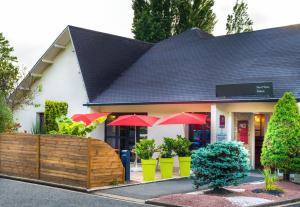 um restaurante com guarda-sóis vermelhos em frente a um edifício em B&B HOTEL Niort Sud Venise Verte em Niort