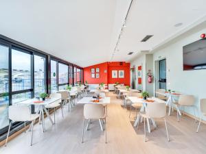 a dining room with tables and chairs and windows at B&B Hotel Milano Aosta in Milan