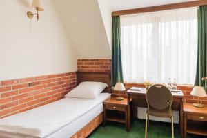 Cette chambre comprend un lit, une table et une fenêtre. dans l'établissement Hotel Szymbark, à Szymbark