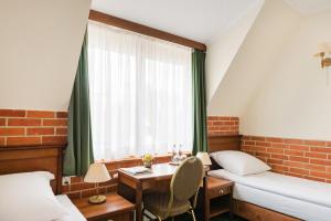 Cette chambre comprend une table, un lit et une fenêtre. dans l'établissement Hotel Szymbark, à Szymbark