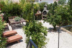 un giardino con 2 panche, un tavolo e una griglia di LIMASSOL AKROTIRI VINE COTTAGE a a Limassol