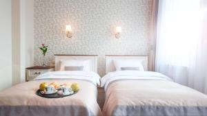 two beds in a room with a tray of food on them at Hotel POD HERBEM -POKOJE OZONOWANE in Białystok