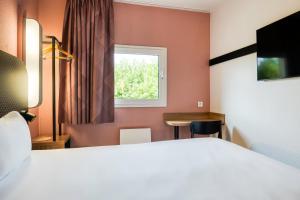 Pokój z łóżkiem, biurkiem i oknem w obiekcie B&B HOTEL Liège Rocourt w mieście Liège