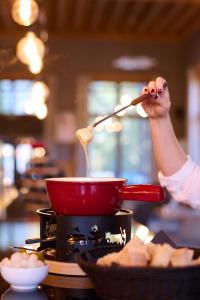 una persona revolviendo una olla en una estufa con una cuchara de madera en Villars Lodge, en Villars-sur-Ollon