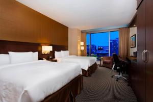 a hotel room with two beds and a desk and a window at Courtyard by Marriott Montreal Downtown in Montréal