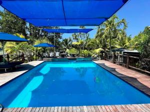 uma piscina exterior com guarda-sóis azuis em Turtle Bay Lodge em Luganville