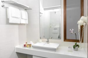 een witte badkamer met een wastafel en een spiegel bij City5 ROOMS & SUITES by LSA in Skopje