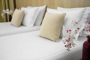 een wit bed met witte kussens en bloemen erop bij City5 ROOMS & SUITES by LSA in Skopje