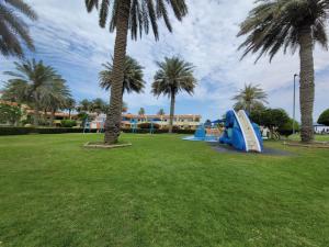 un parque infantil con tobogán en un parque con palmeras en Flamingo Beach Hotel, en Umm Al Quwain