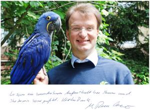 Ein Mann hält einen blauen Papagei in der Unterkunft Hotel Zur Seerobbe in Cuxhaven