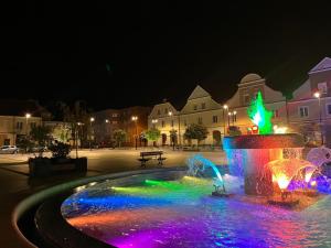 une fontaine aux lumières colorées dans une ville la nuit dans l'établissement Apartamenty Stary Rynek 18, à Łomża