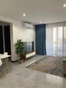 uma sala de estar com uma televisão, uma mesa e uma planta em Urban Awe Apartment- Setlhoa em Gaborone