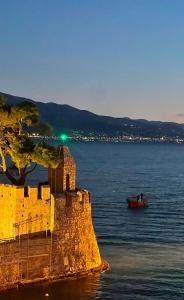 a boat in the water next to a castle at Nostos Luxury Villas with Private Pool in Nafpaktos in Nafpaktos