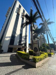 a sign in front of a building with palm trees at Flat Luxuoso Biena Sena Madureira Vila Mariana com garagem 1009 in Sao Paulo