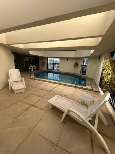 a swimming pool with two chairs and avisor at Flat Luxuoso Biena Sena Madureira Vila Mariana com garagem 1009 in Sao Paulo