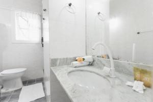 a white bathroom with a sink and a toilet at Peixe Crew Centro in Búzios