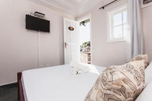 a white bedroom with a bed and a window at Peixe Crew Centro in Búzios