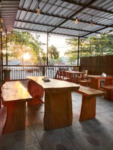 um pátio com mesas de madeira e bancos num pátio em Djembank Hotel & Restaurant em Tjakranegara