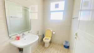 uma casa de banho com um WC amarelo e um lavatório. em Holiday Home Rent villa em Sharjah