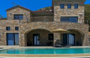 une maison avec une piscine et un parasol dans l'établissement Drys Villas Mekoynida, à Karistos