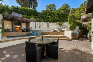 eine Terrasse mit einem Tisch und Stühlen sowie ein Haus in der Unterkunft West Hollywood Hills Jacuzzi and Beautiful View in Los Angeles