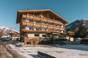 een groot houten gebouw met een balkon in de bergen bij Hotel Arnika in Pozza di Fassa