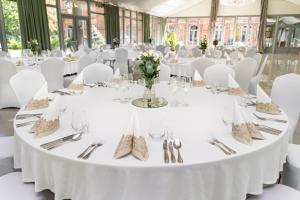 a table set up for a wedding with white tables and silverware at Royal Hotel Modlin in Nowy Dwór Mazowiecki