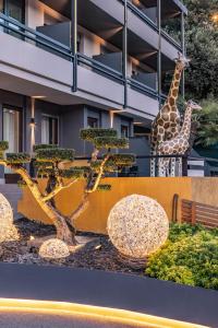 dos jirafas y un árbol delante de un edificio en Hi Hotel - Wellness & Spa, en Trento