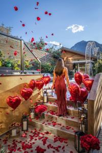 Una mujer caminando por las escaleras con globos de corazón rojos en Hi Hotel - Wellness & Spa, en Trento