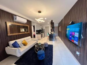 Departamento Inteligente con Jacuzzi Privado en Zapopan في غواذالاخارا: غرفة معيشة مع أريكة وتلفزيون بشاشة مسطحة