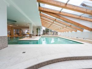 una piscina coperta con soffitto in legno di Alpine Mugon Hotel a Vason