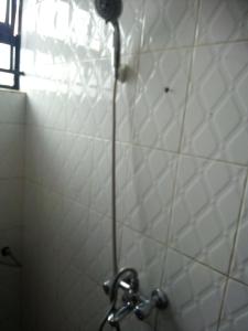 La salle de bains est pourvue d'une douche et de carrelage blanc. dans l'établissement Annonceur Guest House, à Kampala