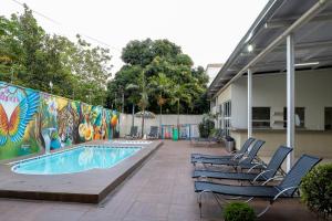 a patio with chairs and a swimming pool with a mural at Allegro Hotel in Goiânia