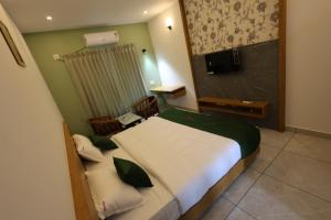 a hotel room with a bed and a television at Riders Den in Mananthavady