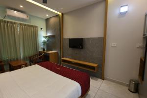 a hotel room with a bed and a television at Riders Den in Mananthavady