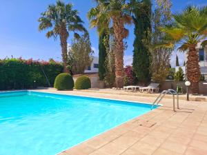 una piscina con palmeras y un edificio en Sunset Green 02, en Pafos