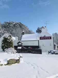 een gebouw bedekt met sneeuw met een bank voor de deur bij The Shandwick Inn in Tain