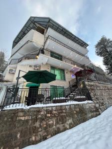 a building with chairs and an umbrella in the snow at Ortus - Murree Hills in Murree