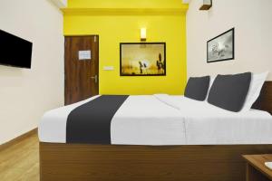 1 dormitorio con 1 cama grande y pared amarilla en Super Hotel O Porvorim Near Mall De Goa, en Panaji