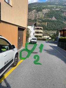 un coche blanco estacionado al lado de un edificio con graffiti verde en Glishorn Blick, en Brig