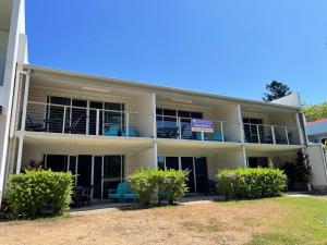 ein Apartmenthaus mit Balkonen, Tischen und Stühlen in der Unterkunft Whitehaven Beachfront Holiday Units in Airlie Beach