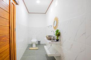 uma casa de banho branca com um lavatório e um WC em Ocean View Private Villa em Nusa Lembongan